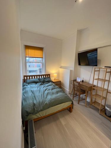a bedroom with a bed and a desk and a television at Camden BNB in London