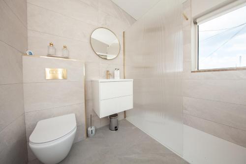 a white bathroom with a toilet and a mirror at Luxe Dublin 4 Retreat with 3 Bedrooms in Dublin
