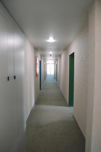 a hallway with a long corridor with white walls and green doors at Campus Inspire Хмельницький in Khmelʼnytsʼkyy