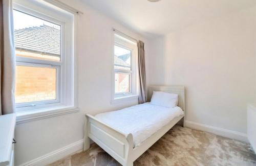 a white room with a bed and two windows at Freshly decorated apartment 10 mins from Cotswolds Child Friendly Great location with plenty of nearby free parking freestanding bath and outdoor private terrace area in Evesham