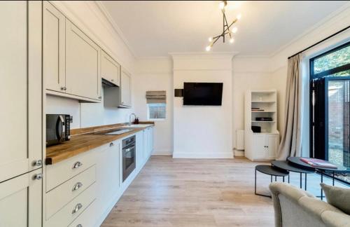 a kitchen with white cabinets and a living room at Freshly decorated apartment 10 mins from Cotswolds Child Friendly Great location with plenty of nearby free parking freestanding bath and outdoor private terrace area in Evesham