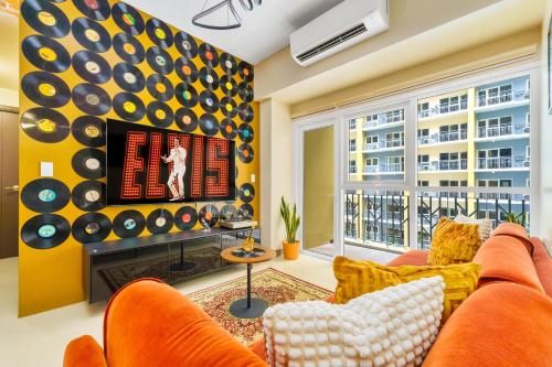 a living room with an orange couch and a tv at Luxury Condo Ocean View 1,2,3, & 4 Bedrooms Infinity Pool Gym Spa Next to Okada Solaire MOA NAIA Airport in Manila