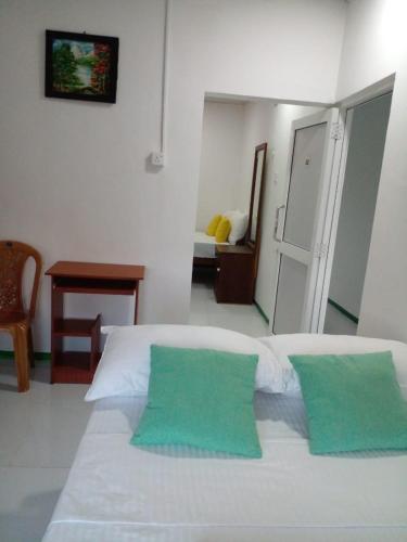 a bedroom with a white bed with two green pillows at lake Edge Dambulla in Dambulla
