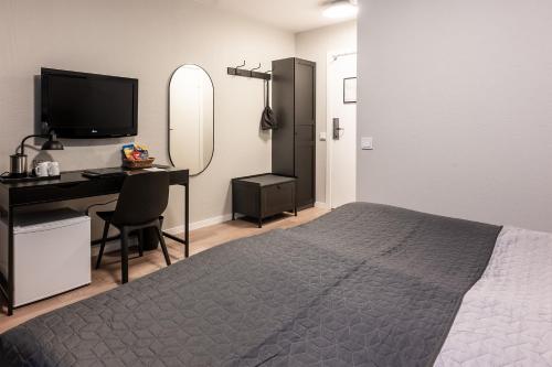 a bedroom with a bed and a desk and a television at Hotel Statt Söderhamn by First Hotels in Söderhamn