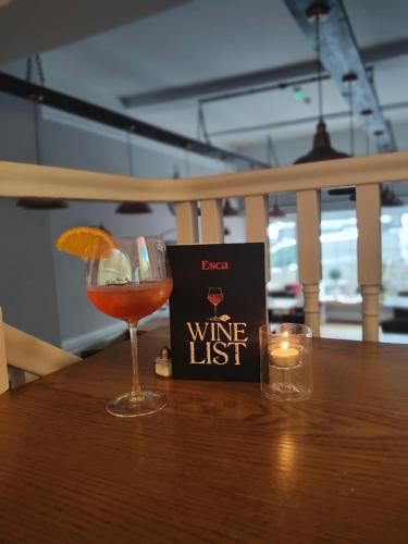 a wine list sitting on a wooden table with a wine glass at Esca with Rooms in Ross on Wye