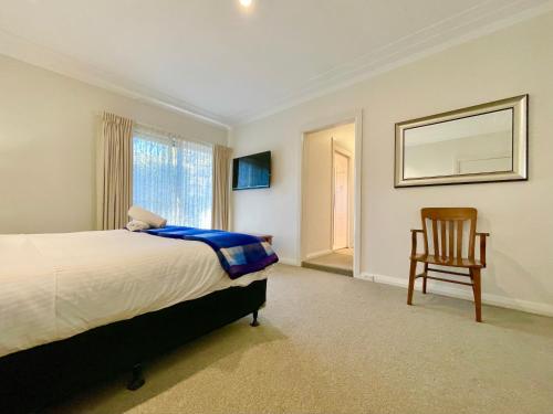 a bedroom with a bed and a chair and a window at Scarlett's Place in Blackheath