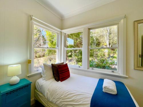 a bedroom with a bed and two windows at Scarlett's Place in Blackheath