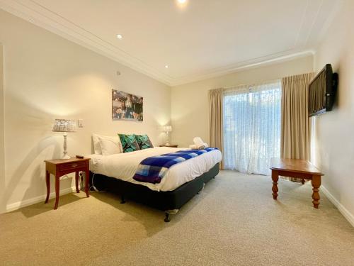 a bedroom with a bed and a television and a window at Scarlett's Place in Blackheath