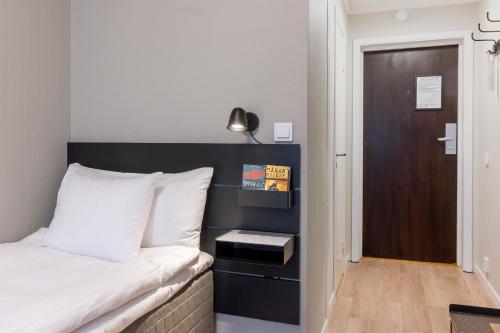a bedroom with a bed with a black headboard and a door at Hotel Statt Söderhamn by First Hotels in Söderhamn