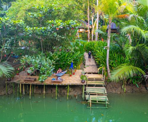 a wooden bridge over a body of water with people on it at Water to Forest Ecolodge in Loboc