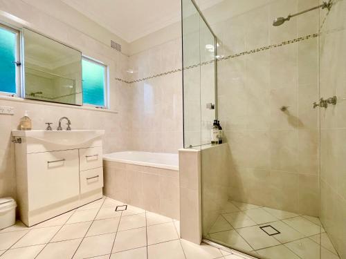 a bathroom with a shower and a tub and a sink at Scarlett's Place in Blackheath