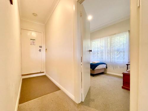 a room with a hallway with a bed and a window at Scarlett's Place in Blackheath