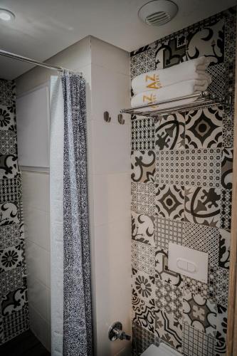 a bathroom with black and white tiles and a shower at AZ hôtel des arts in Rabat