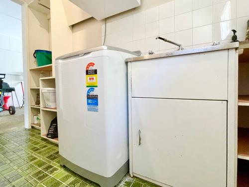 a white refrigerator in a kitchen next to a shelf at Scarlett's Place in Blackheath