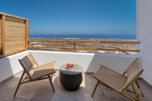 a balcony with two chairs and a table and the ocean at Klοstrá in Foinikiá