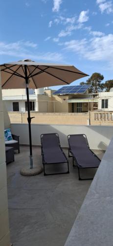 two chairs and an umbrella on a patio at Sea & Sky townhouses in Marsaxlokk