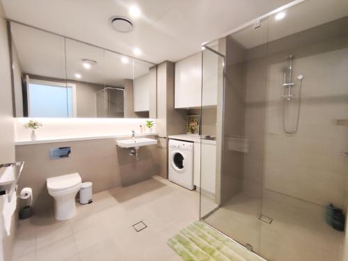 a bathroom with a toilet sink and a washing machine at Cozy Apt w Park View by Stadiums in Sydney