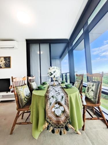 a dining room with a green table and chairs at Cozy Apt w Park View by Stadiums in Sydney