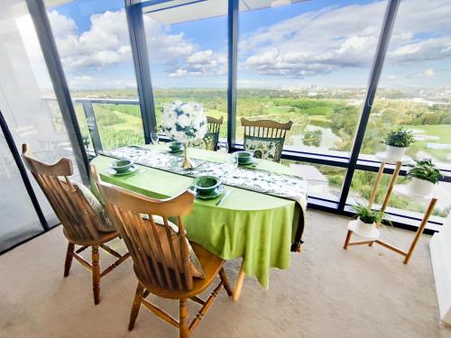 a dining room with a table and chairs and large windows at Cozy Apt w Park View by Stadiums in Sydney
