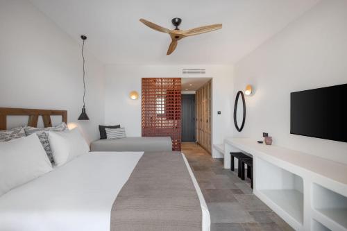 a white bedroom with a bed and a tv at Klοstrá in Foinikiá