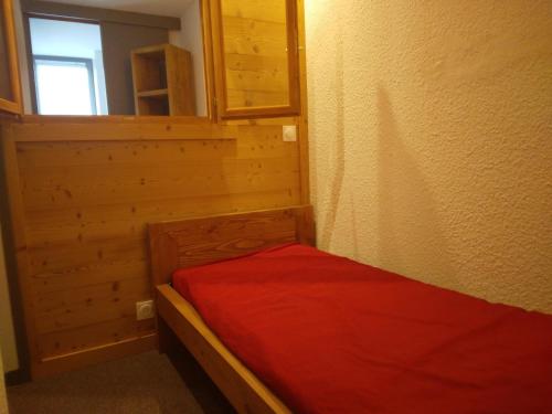 une petite chambre avec un lit avec une couverture rouge dans l'établissement Studio divisible rénové, 4 pers, accès direct pistes, animaux admis - FR-1-181-2385, à La Plagne Tarentaise