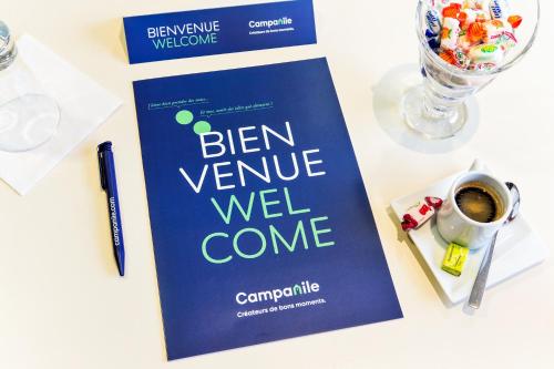 a book on a table with a pen and a cup of coffee at Campanile Mulhouse - Illzach Ile Napoléon in Illzach