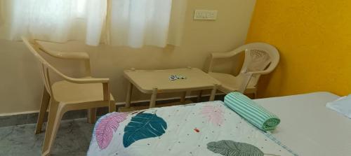 ハンピにあるAshwini home stay hampiの小さなお部屋で、椅子、テーブル、ベッドが備わります。