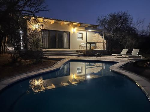 a swimming pool in front of a house at night at Oase by 7 Star Lodges - Greater Kruger Private 530ha Reserve in Hoedspruit