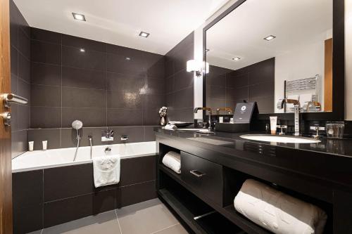 a black bathroom with a tub and a sink at Le Kaïla in Méribel