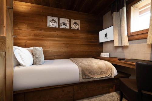 a bedroom with a bed in a wooden wall at Le Kaïla in Méribel