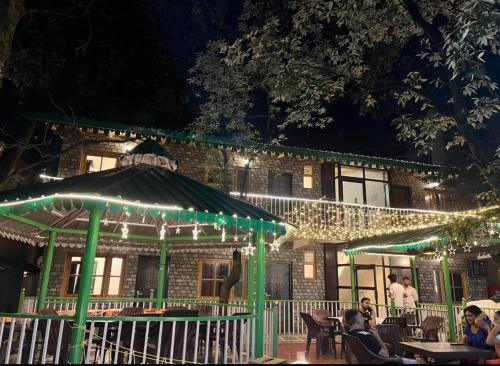 people sitting at tables in front of a building with lights at The Boho Heritage Woods in Nainital