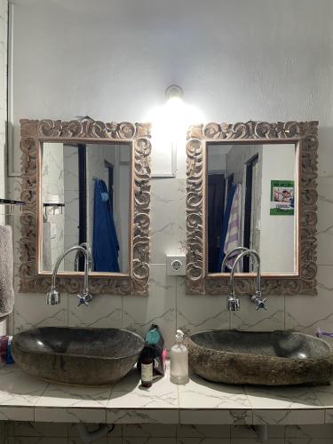 two sinks in a bathroom with two mirrors at WW Backpackers in Ubud