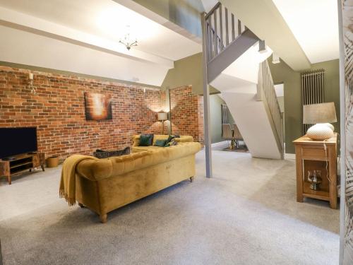 a living room with a couch and a brick wall at Hunters Lodge at Wildersley Farm in Belper