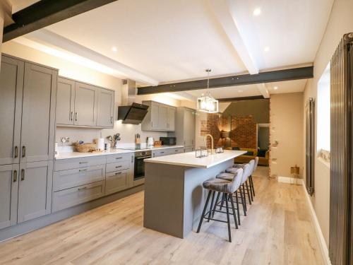 a kitchen with white cabinets and a island with bar stools at Hunters Lodge at Wildersley Farm in Belper