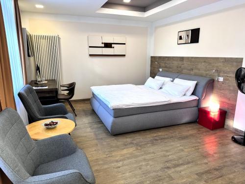 a bedroom with a bed and a couch and chairs at Hotel PrimaVera parco in Fürth