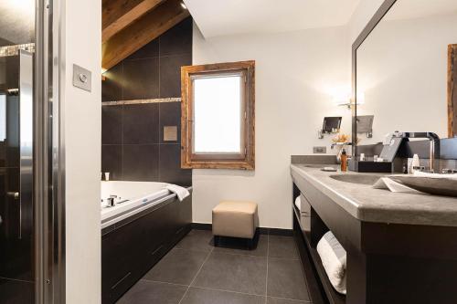 a bathroom with a tub and a sink at Le Kaïla in Méribel