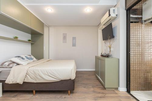 Un dormitorio con una cama y un televisor en una pared. en Seu lar no coração de Curitiba, en Curitiba