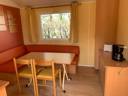 a table and chairs in a small room with a window at Camping La Saline d'Arc et Senans in Arc-et-Senans