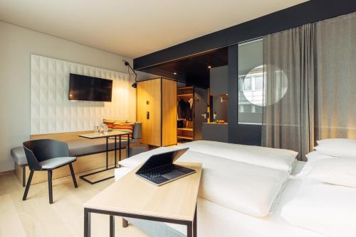 a hotel room with a bed and a desk with a laptop at harry's home Zürich-Limmattal in Spreitenbach