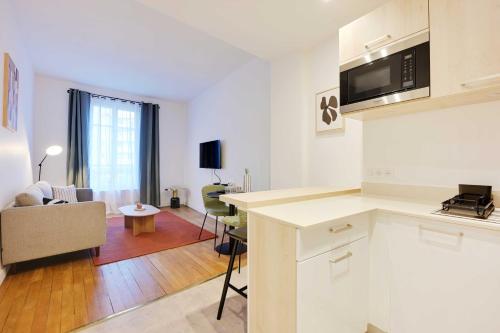 une cuisine avec des armoires blanches et un salon dans l'établissement Cosy apartment - 1BDR-4P - Boulogne Billancourt, à Boulogne-Billancourt