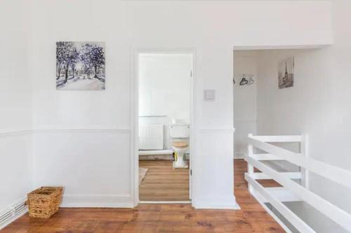 a room with white walls and wooden floors and a staircase at Cheerful Maisonette in the heart of Orrell Park in Liverpool