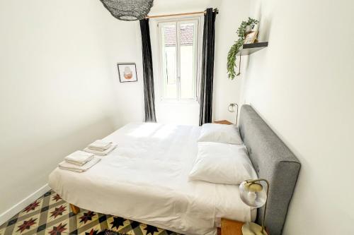 Cette petite chambre comprend un lit avec des draps blancs et une fenêtre. dans l'établissement AC - Private Parking - Close to the ramparts, à Avignon