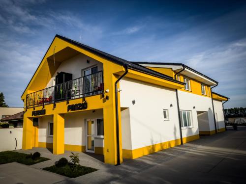 a yellow and white building with a balcony at Penzión Tulipán in Jelka