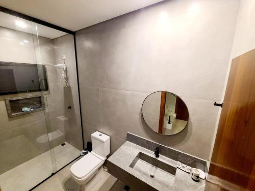 a bathroom with a toilet and a sink and a mirror at Linda casa a 200m da Praia do Capricórnio in Massaguassu