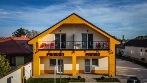 a yellow and white house with a balcony at Penzión Tulipán in Jelka