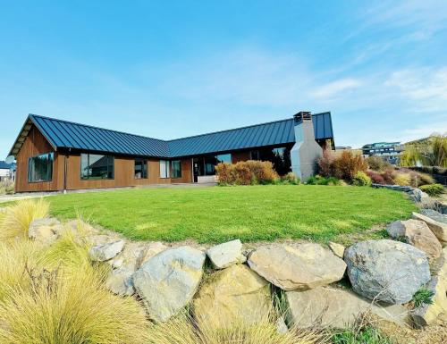 a house with a green yard and rocks at Cedar Lakeview in Lake Tekapo