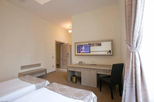 a room with two beds and a desk and a tv at Euro Hotel Grivita in Bucharest