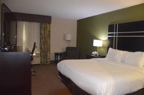 a hotel room with a large bed and a chair at Comfort Inn & Suites Maumee - Toledo I80-90 in Maumee