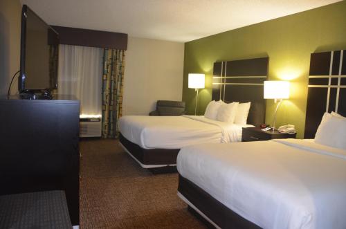 a hotel room with two beds and a chair at Comfort Inn & Suites Maumee - Toledo I80-90 in Maumee
