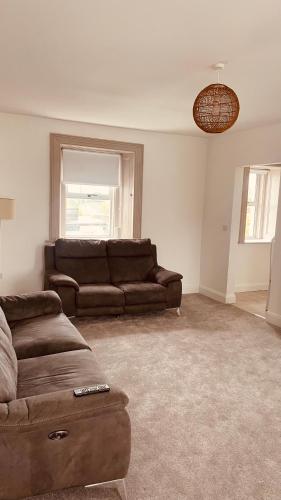 a living room with a brown couch and a window at Colton House - Apt 4 in Tullamore
